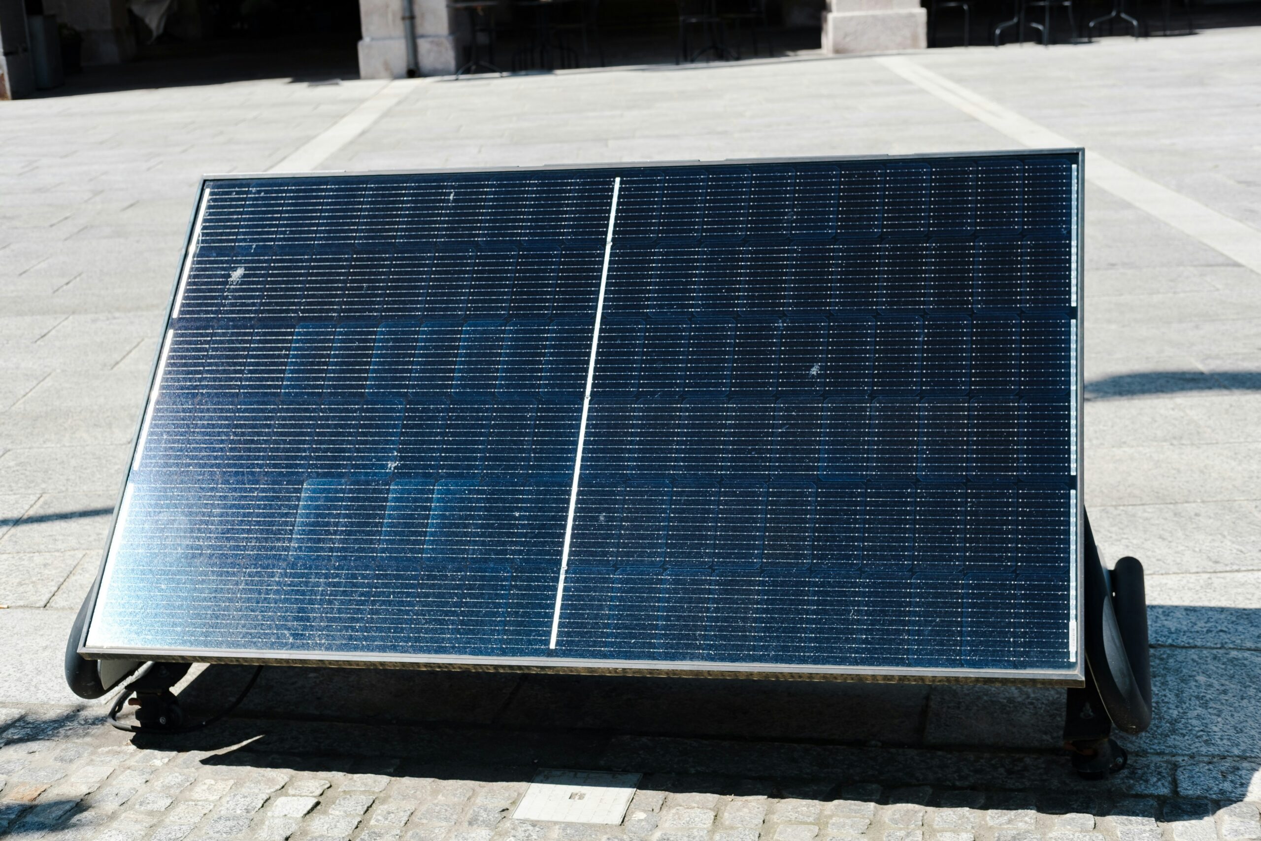 le solar panel installed outdoors on a paved surface under bright sunlight.